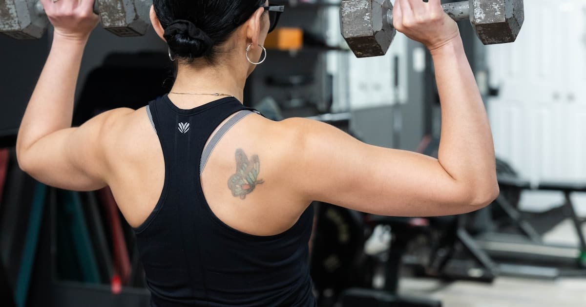 Woman performing overhead dumbbell presses during a strength training session